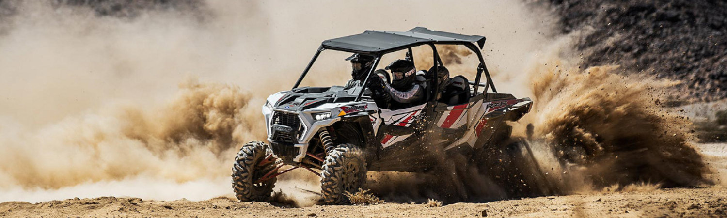 Two people on a 2022 Polaris® side by side turning aggressively onto a dirt curb.